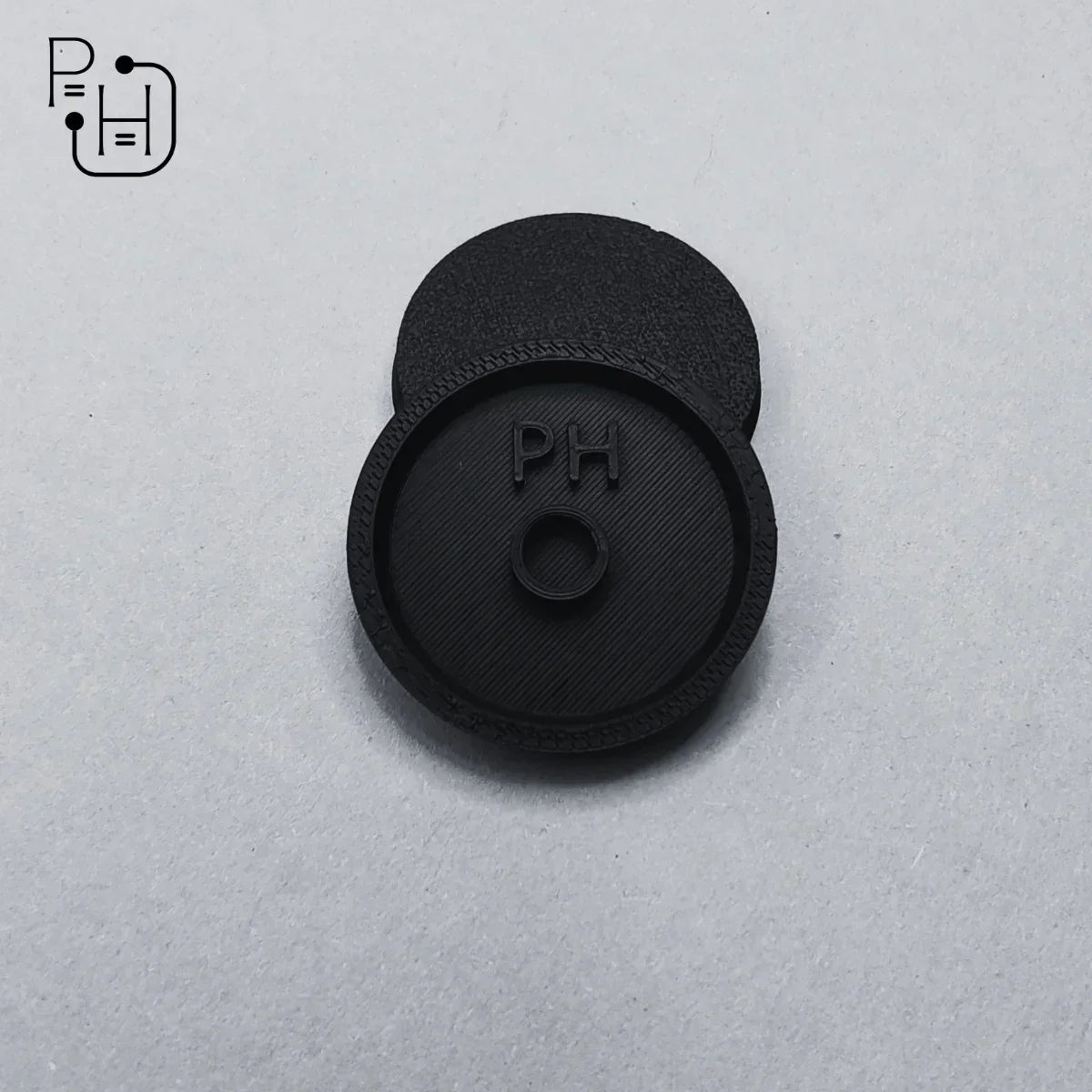 Black 3D printed PH logo base for wargaming miniatures, textured surface, circular design