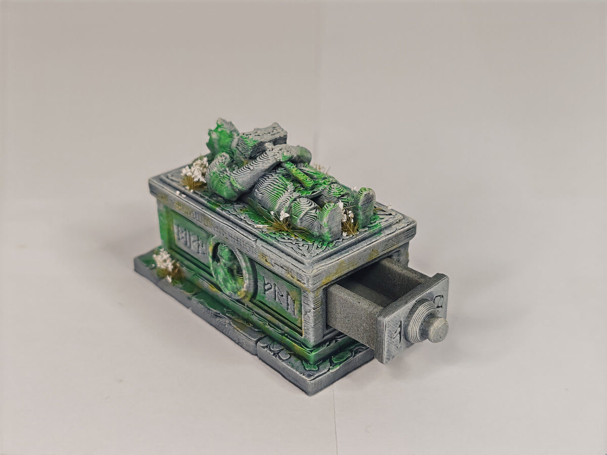 A miniature fantasy collectible figurine depicting a green-skinned zombie-like creature lying on top of a gray stone sarcophagus with one drawer pulled open, set against a plain light gray background.