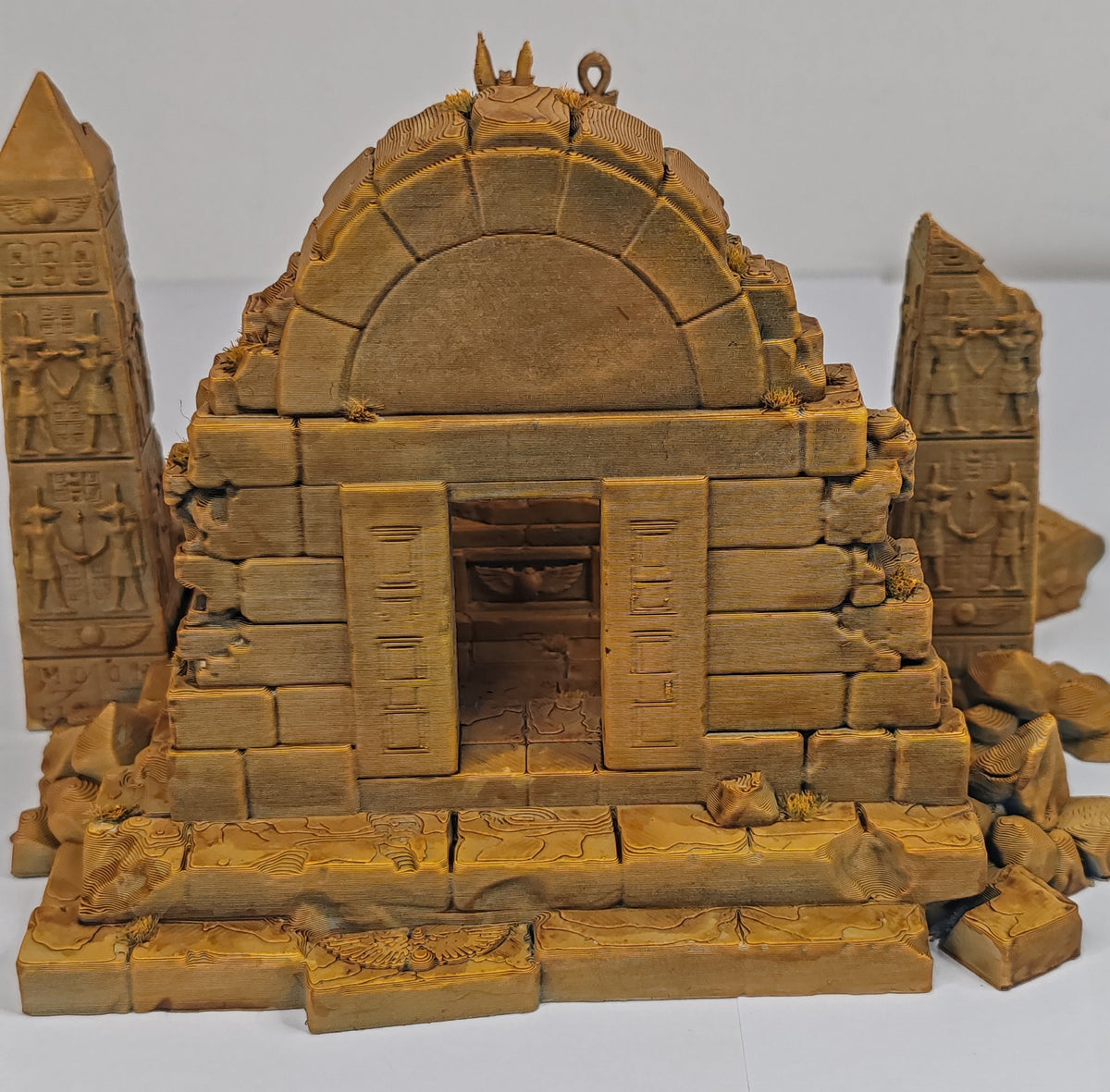 A miniature model of an ancient stone temple or tomb with a domed roof, carved pillars, and detailed hieroglyphic patterns, shown on a plain white background.